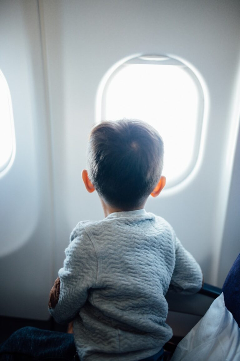 toddler sitting on plane seat while viewing window