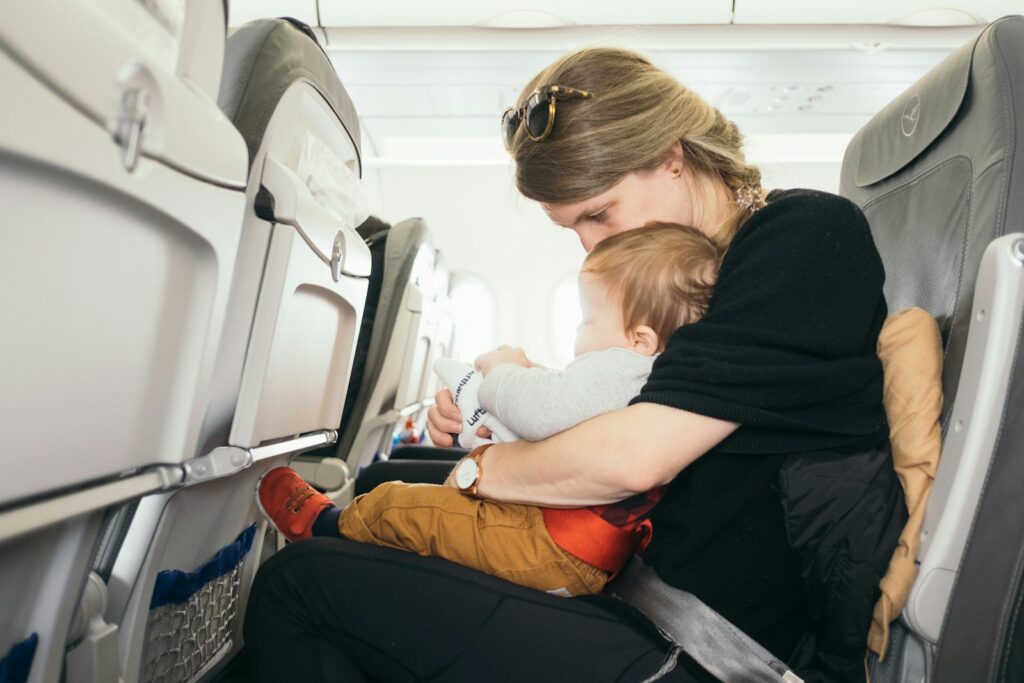 woman carrying baby while traveling on pane