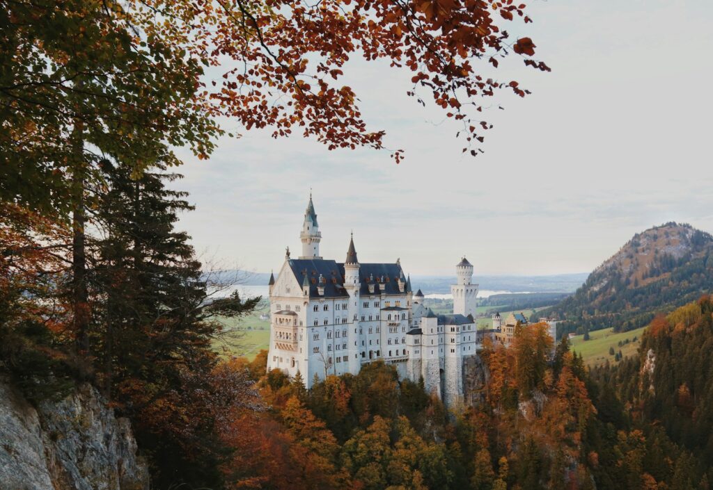 a large white castle sitting on top of a lush green hillside
