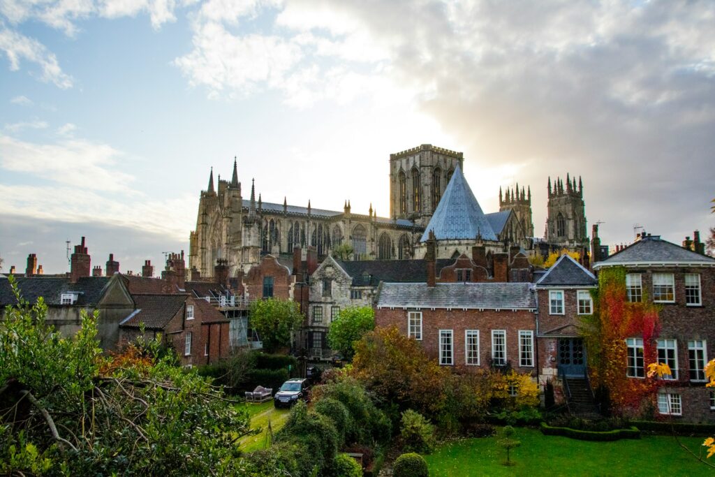 brown concrete building near green trees under white clouds during daytime