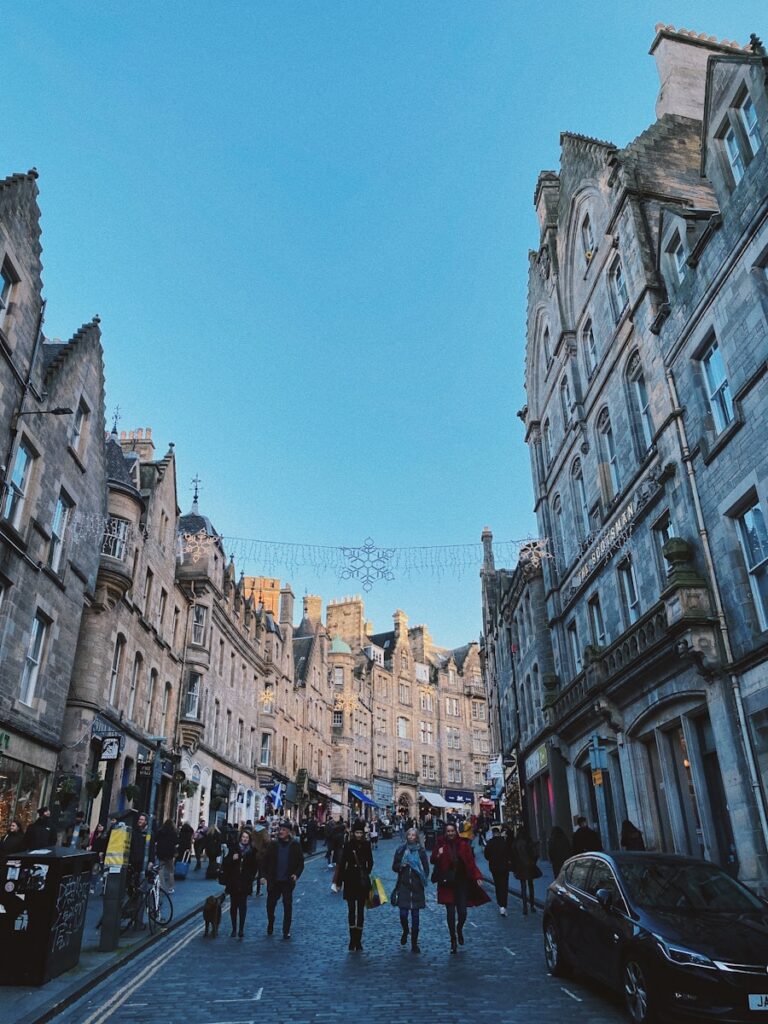 A group of people walking down a street next to tall buildings