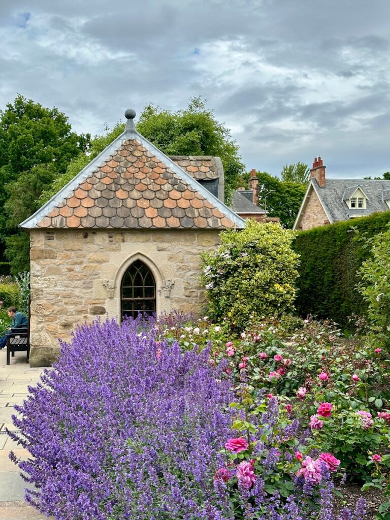 A stone building surrounded by flowers and trees