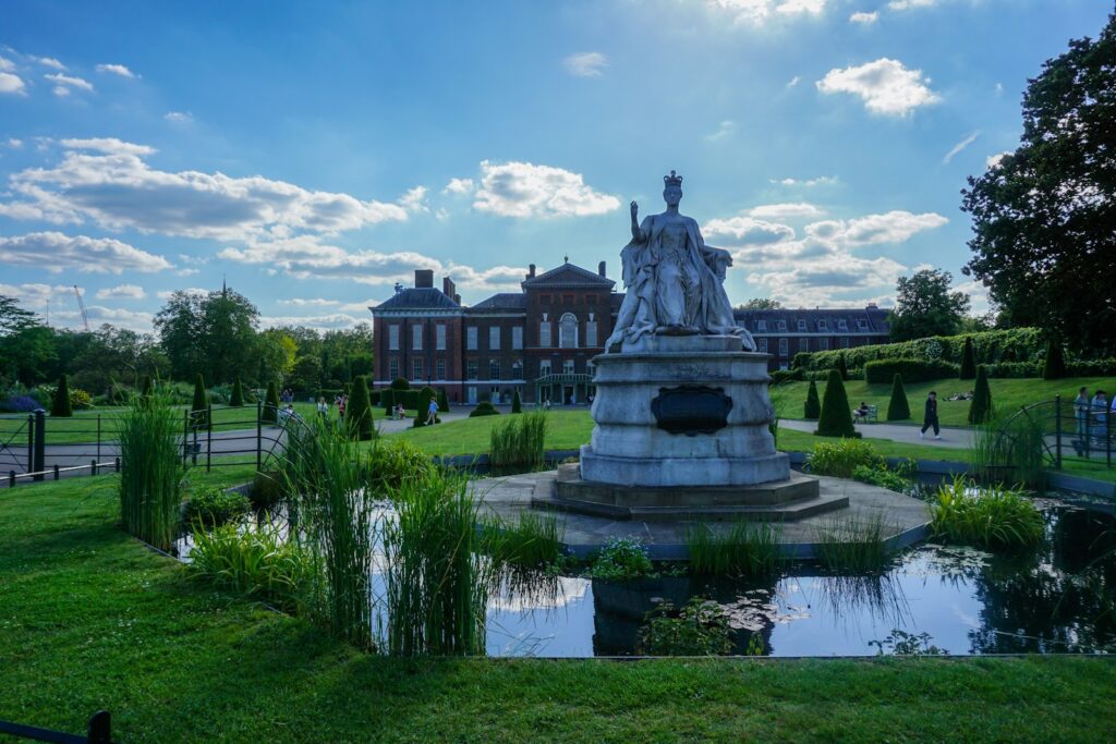 a statue in the middle of a park with a building in the background