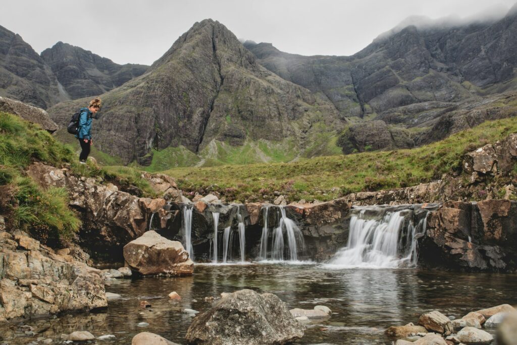 a man standing on a rock near a waterfall