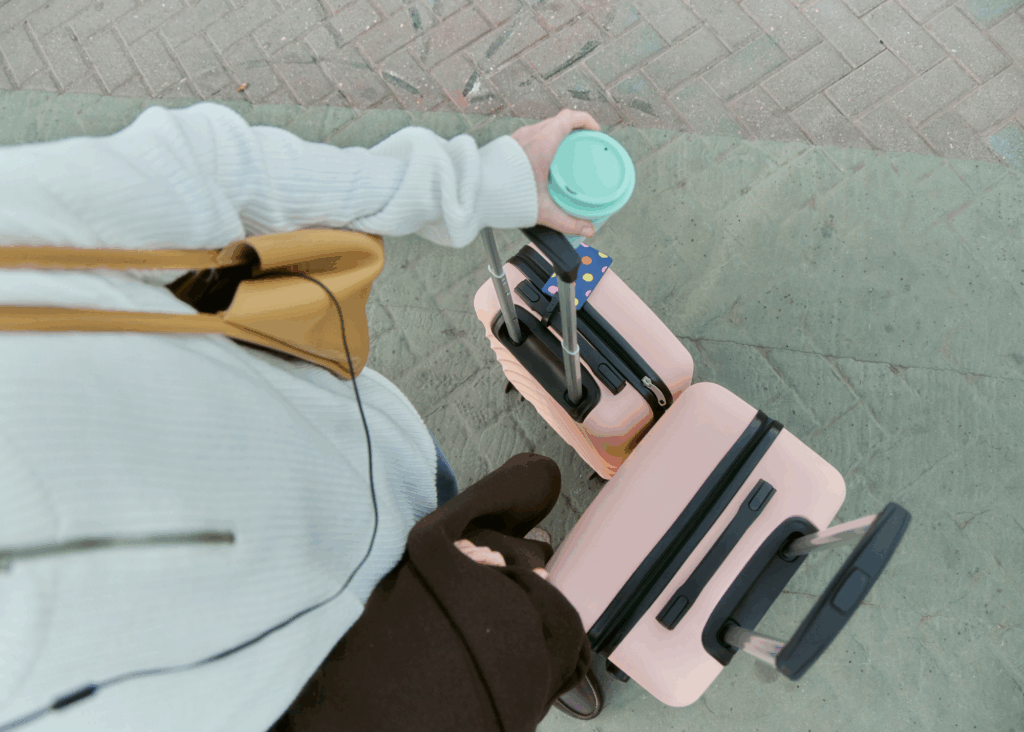 woman traveling with pink suitcases and a coffee to go 