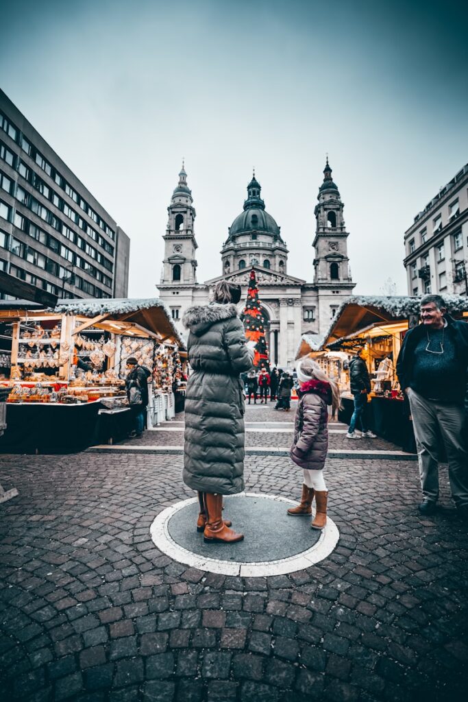 a woman and child standing in front of a christmas market