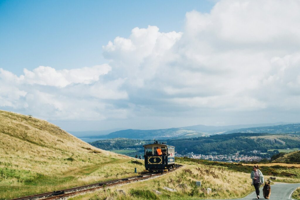 A couple of people walking down a road next to a train