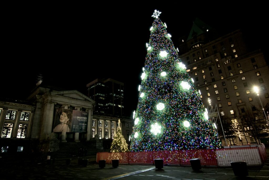 a large christmas tree is lit up in a city square