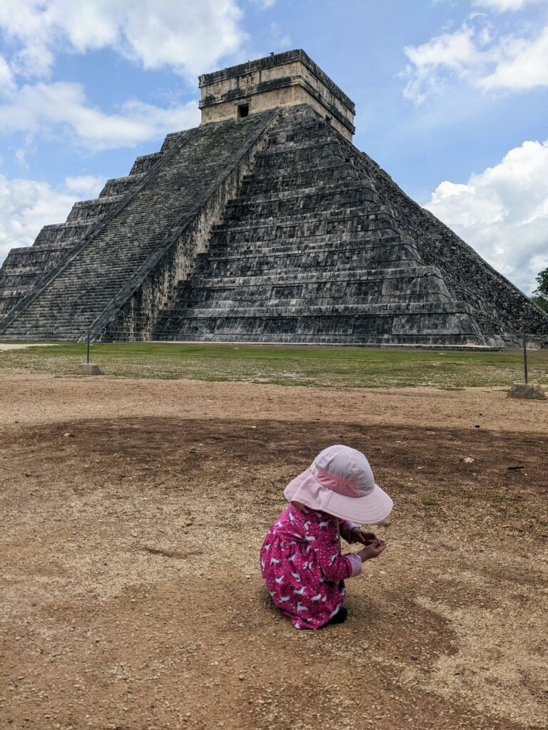 toddler playing with rocks at Chichen Itza during the day