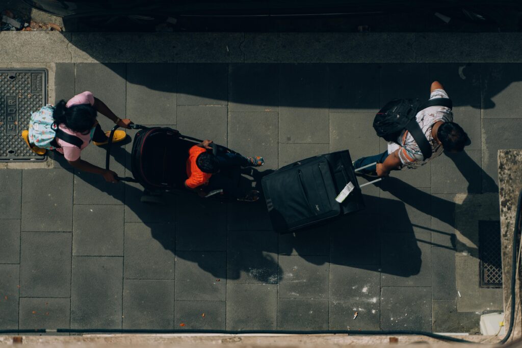 Aerial view of travelers with luggage and a stroller on a Rome street.